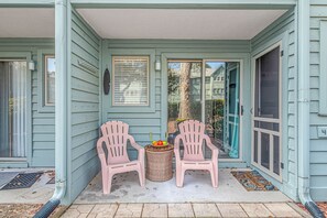 Relax on the porch with two Adirondack chairs facing each other, accompanied by a small table and a wicker basket.