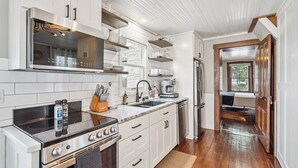 A modern kitchen with white cabinetry, stainless steel appliances, and a wooden floor.