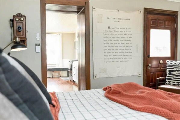 A bedroom with a bed, a wall clock, a door, and a poster.