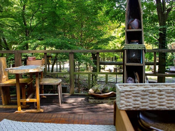 Une terrasse en bois avec une table et des chaises, entourée d’une végétation luxuriante.