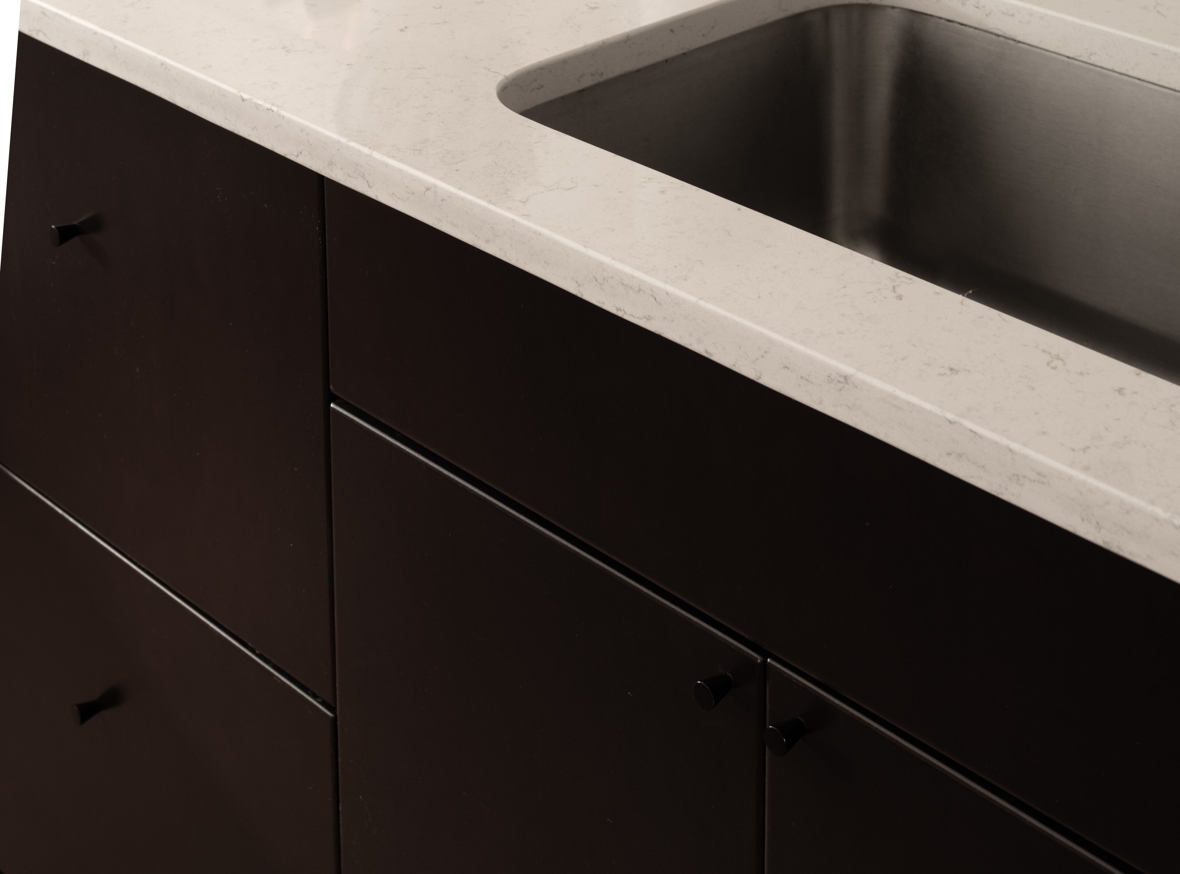 A kitchen with dark cabinets and a white countertop.