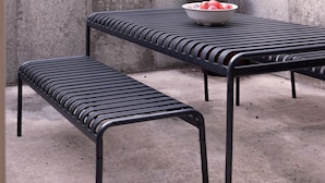 A concrete wall with a metal table and bench.