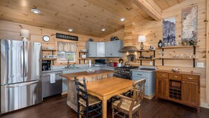 Cocina moderna con paredes de madera, electrodomésticos de acero inoxidable y una isla central con sillas.