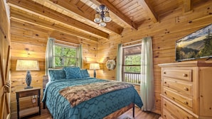 Un dormitorio de cabaña de madera con cama, cómoda y un cuadro en la pared.