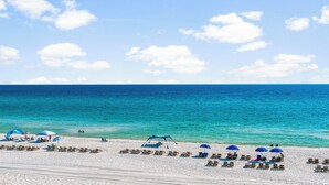 Une plage de sable blanc, avec une eau turquoise et limpide, quelques parasols et des chaises longues.