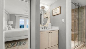 Une salle de bain moderne avec un grand miroir, un lavabo et une douche.