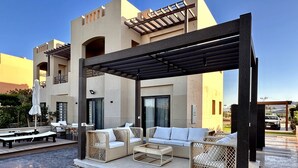 Un espacio al aire libre con mobiliario de mimbre y una pérgola.