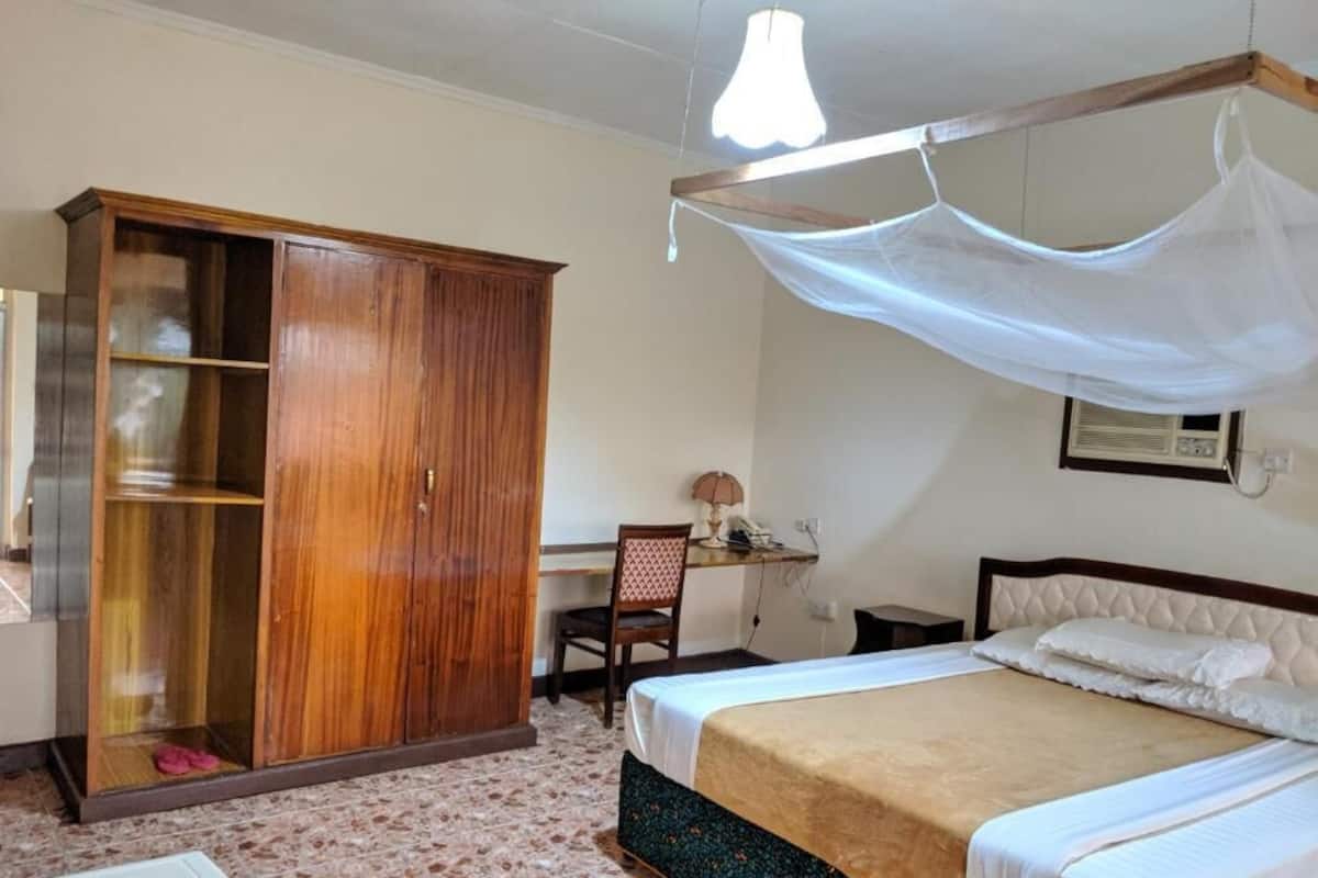 A bedroom with a bed, a wardrobe, a desk, and a chair.