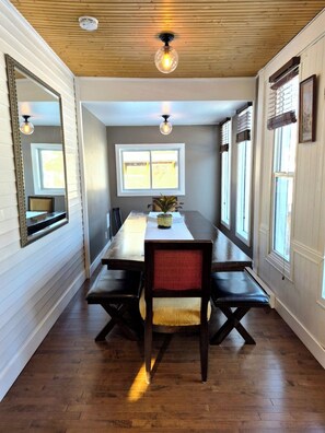 A dining area with a wooden table, benches, and a ceiling light fixture. - Beautiful character home in the heart of down town Banff. (Banff)