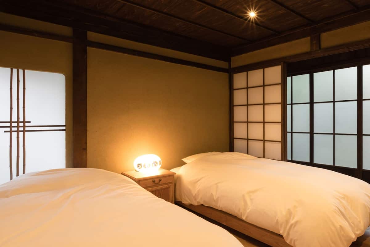 Een traditionele Japanse kamer met tatami vloerbedekking, een laag houten plafond en verschuifbare shoji deuren.