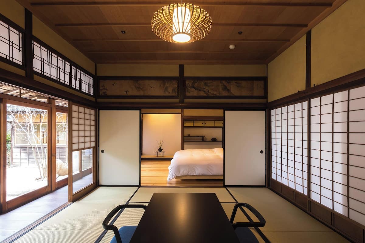 Een traditionele Japanse kamer met tatami vloerbedekking, een lage tafel en een bed.