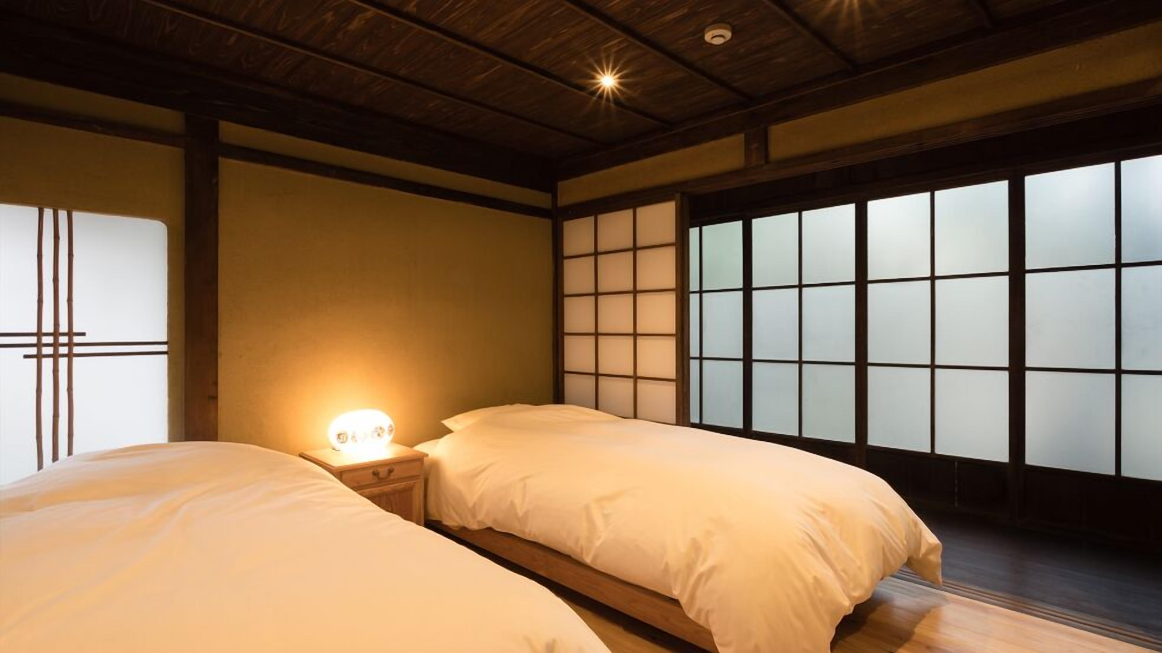 Een traditionele Japanse kamer met tatami vloeren, een laag houten plafond en een wand van shoji schermen.