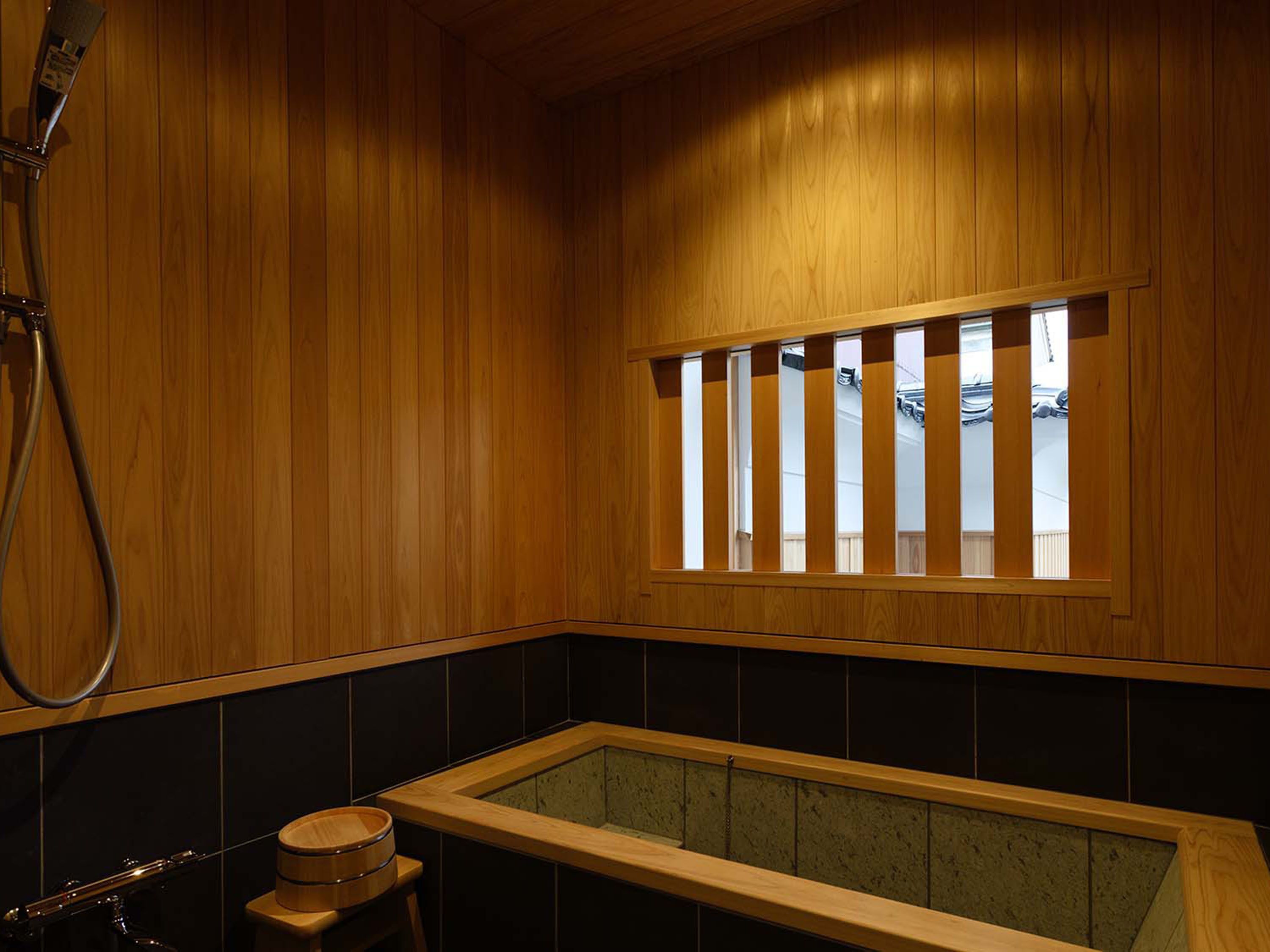 A wooden interior with a bathtub, a window with vertical blinds, and a towel rack.