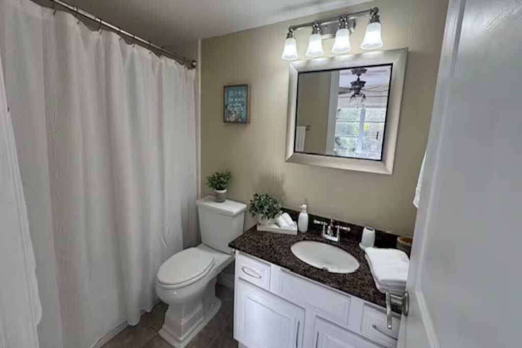 Un baño con inodoro, lavamanos y cortina de ducha.