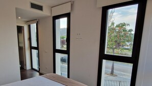 Un dormitorio con una cama grande, una ventana con vistas al exterior y una puerta que da a otra habitación.