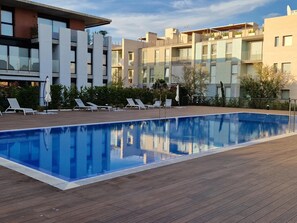 Un espace piscine moderne avec une terrasse en bois et des chaises longues.