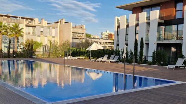 Un hotel moderno con piscina, sillas de descanso y terraza de madera.