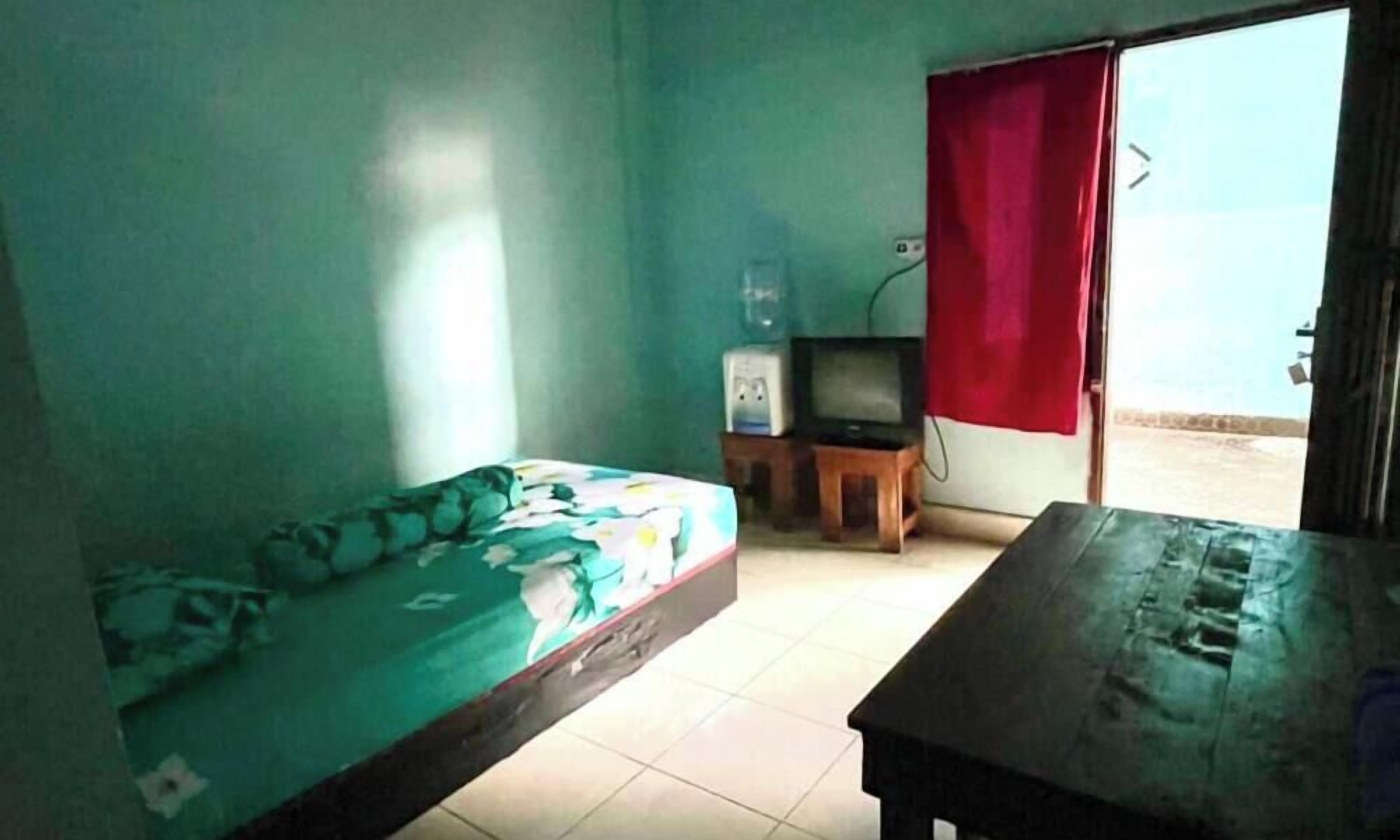 Una habitación con una cama, una mesita, un televisor y una ventana con cortina roja.