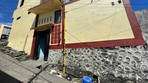 Un edificio con fachada amarilla y base roja, que presenta una pequeña entrada y una ventana.