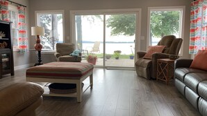 Un salon spacieux avec une grande fenêtre, un canapé, un fauteuil et une petite table.