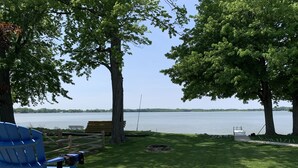 Un parc au bord du lac, avec un banc en bois, une chaise bleue et un foyer.