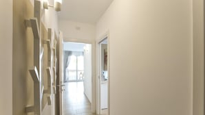 Corredor com luminária moderna e porta que dá para um quarto.
