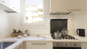 Cozinha moderna com fogão a gás, forno e janela com vista para um edifício.