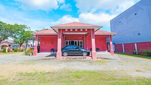 Un bâtiment à la façade rouge avec une voiture garée devant.