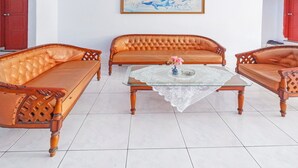 Un salon avec une table basse en verre, deux canapés en cuir marron et une table d’appoint en bois.