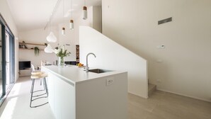 Cozinha moderna com ilha central, luminárias pendentes e uma pia embutida.