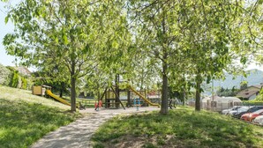 Ein Park mit einem gepflasterten Weg, Spielgeräten und Bäumen.