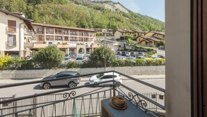 Ein Hotel mit mehreren Etagen, Balkonen und Blick auf eine Straße mit geparkten Autos sowie eine hügelige Landschaft im Hintergrund.