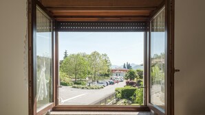 Ein Zimmer mit großem Fenster und Blick auf einen Parkplatz sowie Grünflächen.
