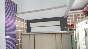 Een receptiebalie met de tekst 'RECEPTION', modern design, een paarse baksteenmuur en een ShowCase display unit.