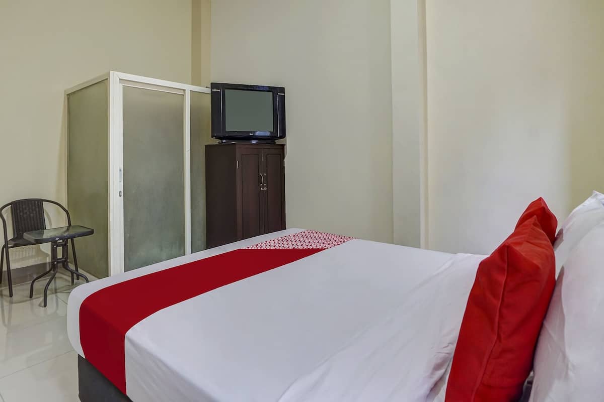 Una habitación de hotel con una cama, un televisor sobre un mueble y una silla.