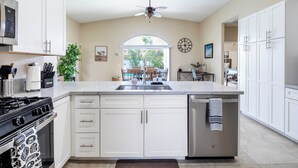 Una cocina moderna con muebles blancos, un lavamanos de acero inoxidable y un lavavajillas.