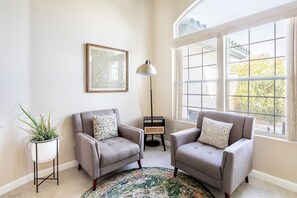 Relax in a stylish living room with two armchairs, a colorful rug, and a floor lamp.