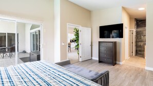 Un dormitorio moderno con una cama grande, un televisor montado en la pared y un ventanal corredero que da a un balcón.