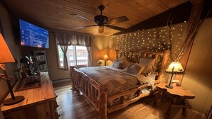 A cozy bedroom with a wooden bed, a ceiling fan, and string lights. - Lake view 2 bedroom House on Lake Delton Resort. Beaches. Pool. Playground! (Lake Delton)