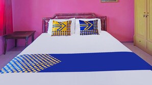 A bed with two pillows, a wooden nightstand, and a wardrobe in a room with pink walls. - SPOT ON 91527 As-sakinah Homestay Syariah (Surabaya)