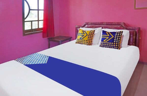A bed with a white and blue bedspread, two pillows with yellow and blue patterns, and a wooden headboard. - SPOT ON 91527 As-sakinah Homestay Syariah (Surabaya)