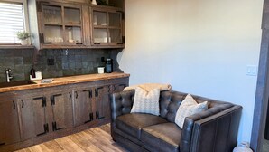 Una cocina moderna con armarios de madera oscura, encimera de madera y sofá de cuero con cojines estampados.