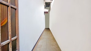 A narrow hallway with white walls and a tiled floor. - OYO LIFE 91551 Gwen Syariah Homestay (Jogoroto)