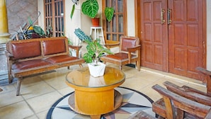 A lobby with a round table, wooden chairs, a sofa, and a potted plant. - OYO LIFE 91551 Gwen Syariah Homestay (Jogoroto)