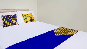 A bed with white bedding and blue and yellow patterned pillows. - OYO LIFE 91551 Gwen Syariah Homestay (Jogoroto)