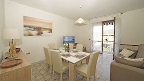 A dining area with a table set for four, a television, and a view of the outdoors through a door. - Casa Pel r in Toscolano Maderno (Toscolano Maderno)