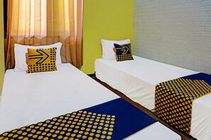 A hotel room with two single beds, each with a white bedspread and matching pillows. The room has a green accent wall and a window with sheer curtains. - OYO Life 91931 Permata Brantas Syariah Homestay (Jombang)