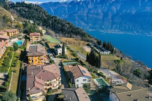 A residential area with houses, a swimming pool, and a view of a lake and mountains. - Appartamento Anna 701 (Tignale)