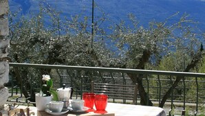 A table set outdoors with a mountain view, a lamp, and a railing. - Appartamento Anna 701 (Tignale)