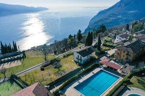 Vista aerea di una zona residenziale con piscina, case e vista sul lago.